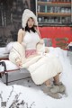 A woman sitting on a bench in the snow.