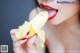 A woman is eating a banana with her tongue out.