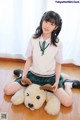 A young woman sitting on the floor with a stuffed animal.