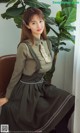 a woman sitting on top of a chair next to a plant