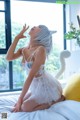 A woman in a white cat costume sitting on a bed.