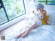 A woman in a white cat costume sitting on a bed.