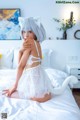 A woman in a white cat costume sitting on a bed.