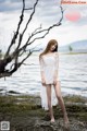 A woman in a white dress standing by the water.