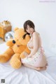 A woman sitting on a bed with a teddy bear.