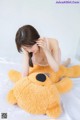 A woman laying on a bed with a large teddy bear.