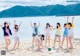 A group of young women standing on top of a sandy beach.