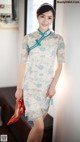 A woman in a blue and white cheongsam posing for a picture.