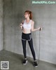 A woman in a white sports bra top and black leggings holding a skipping rope.