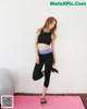 A woman in a black sports bra top and black leggings doing a yoga pose.