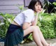 A woman in a school uniform sitting on a bench.