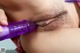 A close up of a person holding a purple dildo.