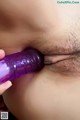 A close up of a person holding a purple dildo in their mouth.