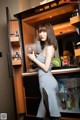 A woman standing in front of a refrigerator holding a glass of wine.