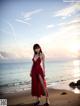 A woman in a red dress standing on a beach.