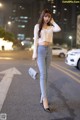 A woman standing in the middle of a city street at night.