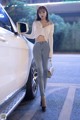 A woman standing next to a white car in a parking lot.