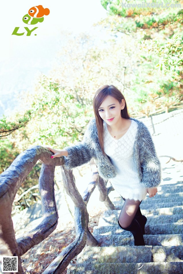 A woman in a white dress and fur coat standing on some stairs.