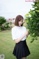 A woman in a white shirt and black skirt posing for a picture.