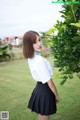 A woman in a white shirt and black skirt posing for a picture.