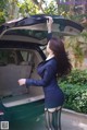 A woman in a business suit standing next to a car.