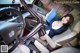 A woman sitting in the driver's seat of a car holding a book.