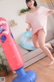 A woman in a pink shirt is jumping on an inflatable punching bag.